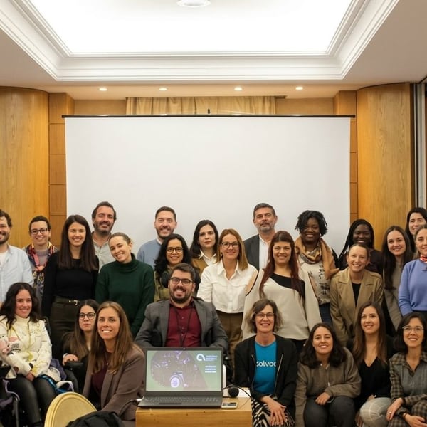 Um grupo numeroso reunido para uma fotografia numa sala de eventos de hotel.