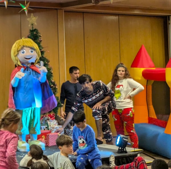 Crianças numa festa de Natal num hotel, com figurantes caracterizados.