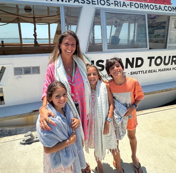 Uma guia e crianças em frente a um barco de passeios às ilhas da Ria Formosa.