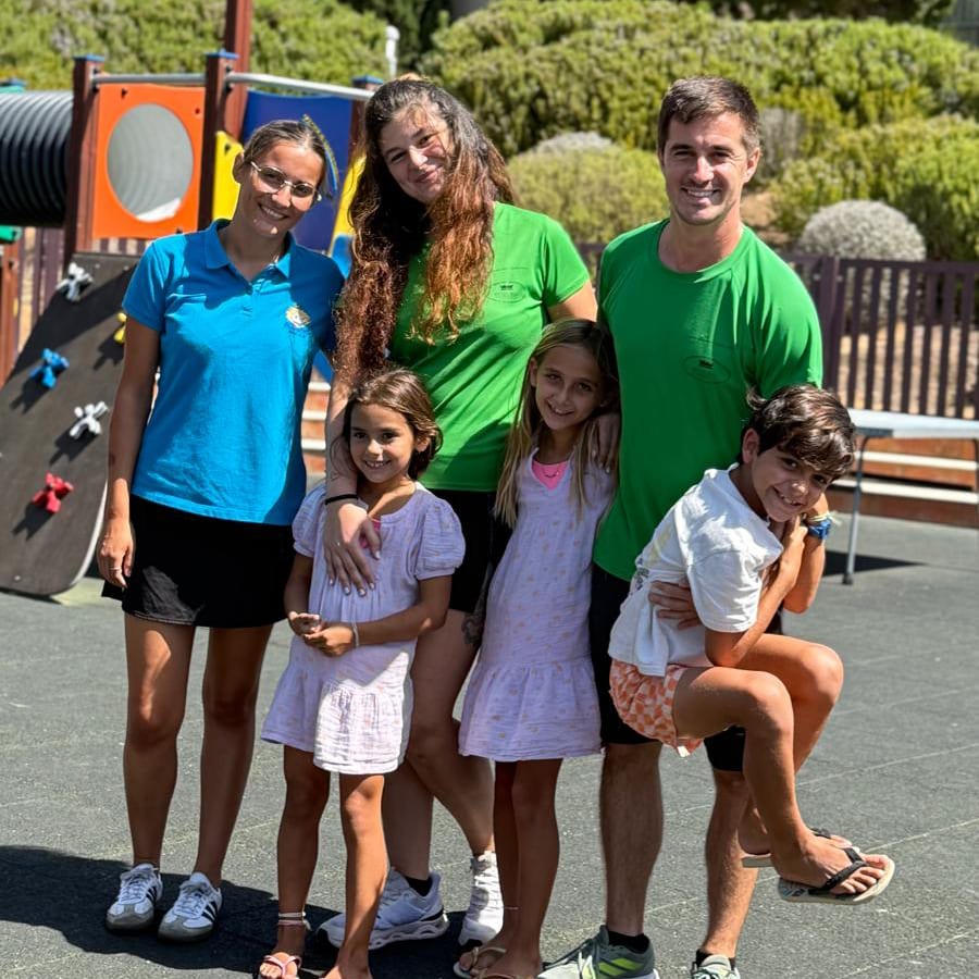 Colaboradores e crianças juntos num parque infantil de hotel, num dia de verão.