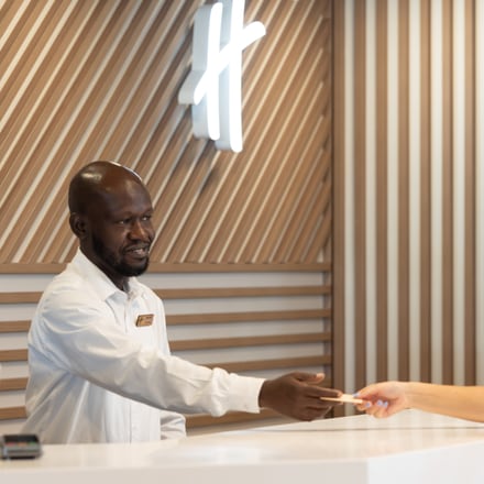Um colaborador na receção de um hotel, a entregar um cartão-chave sobre o balcão.