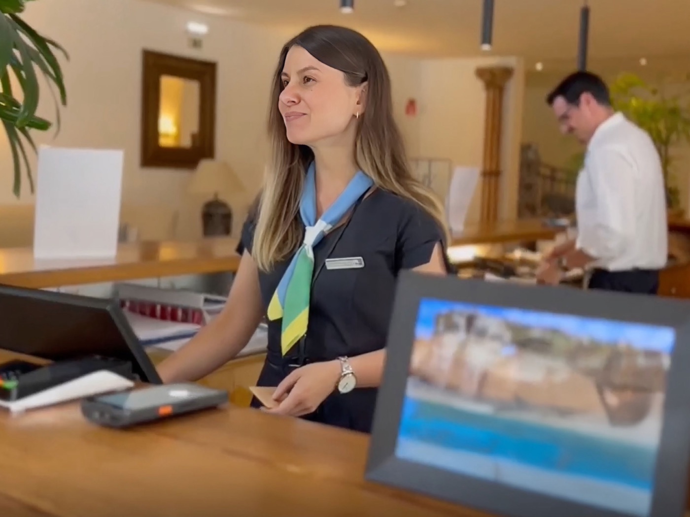 Dois colaboradores fardados a trabalhar na receção de um hotel.