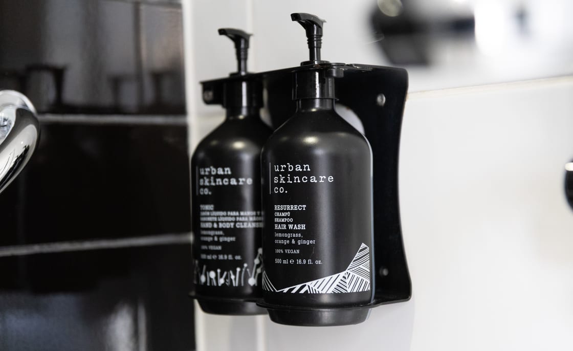 Dispensadores de amenities recarregáveis montados na parede azulejada de uma casa de banho.