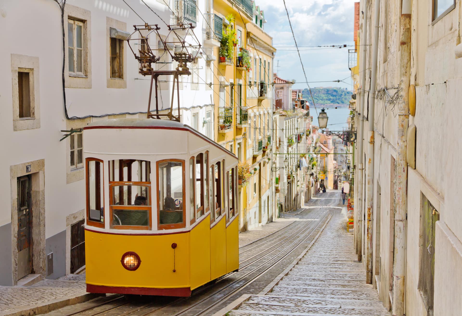 Um elevador amarelo a subir uma rua estreita de Lisboa.